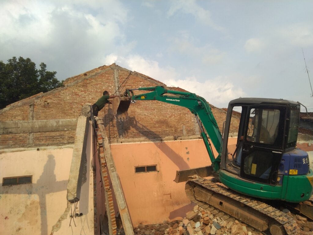 Proses jasa bongkar rumah di Jogja menggunakan excavator dan tenaga profesional.