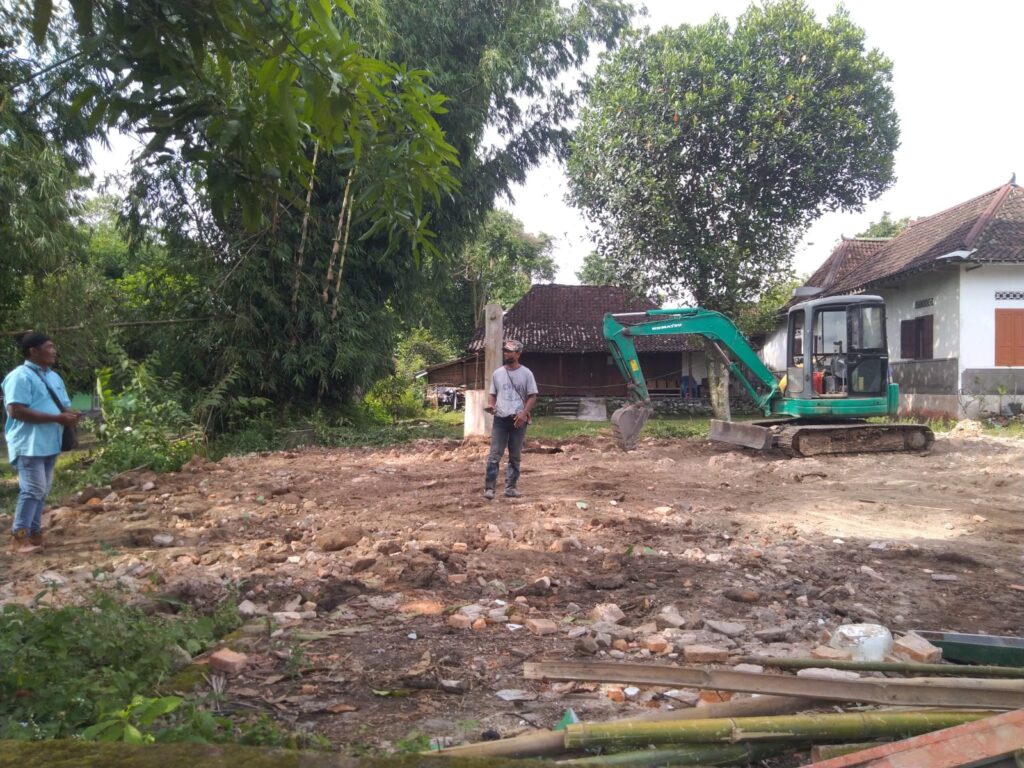 Area lahan setelah pembongkaran bangunan rumah di Jogja, terlihat tanah sudah rata dengan sisa puing bangunan yang telah dibersihkan menggunakan excavator dan siap untuk tahap pembangunan berikutnya.